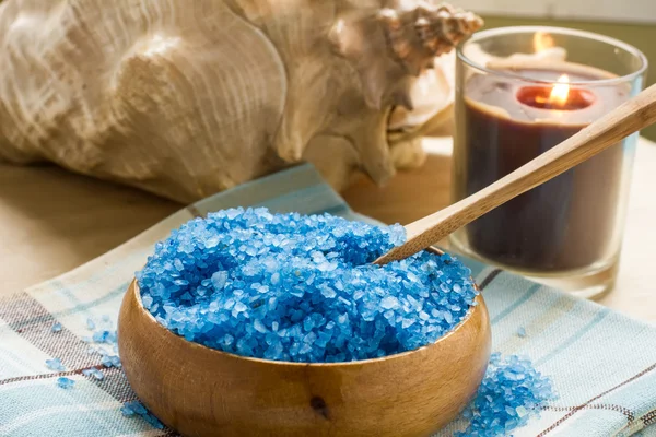 Sea salt in bowl with candle and towels on wooden background — Stock Photo, Image