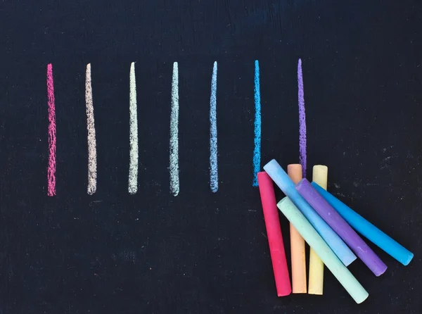 stock image Set of colorful pieces of chalk on blackboard