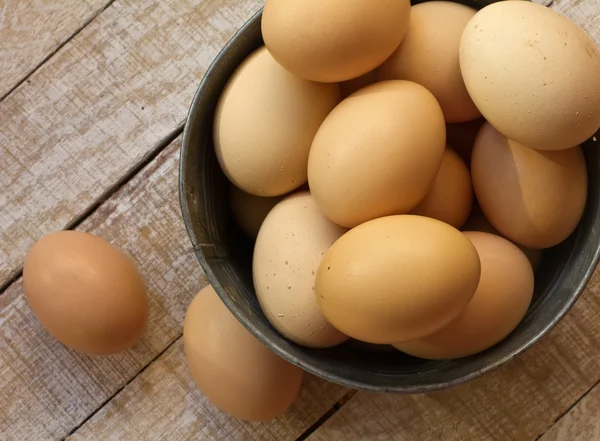 Verse eieren in metalen kom op oude houten achtergrond — Stockfoto
