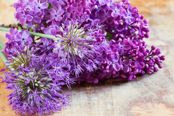 Fresh flowers of allium and lilak on wooden table — Stock Photo, Image