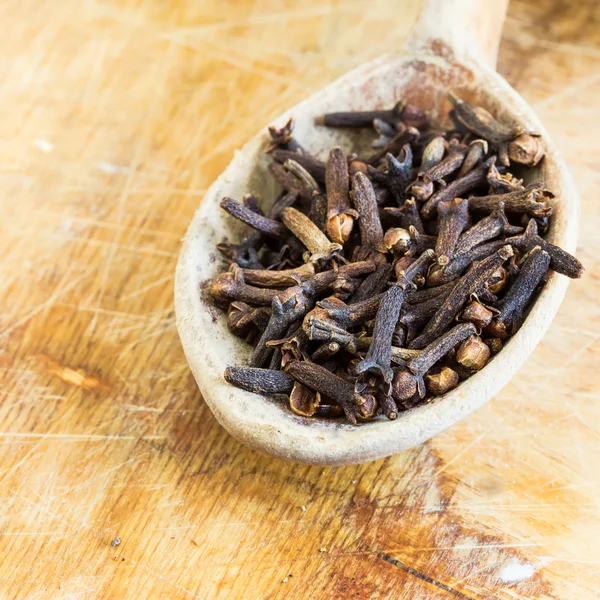 Group of spaces with cloves on wooden background Stock Photo