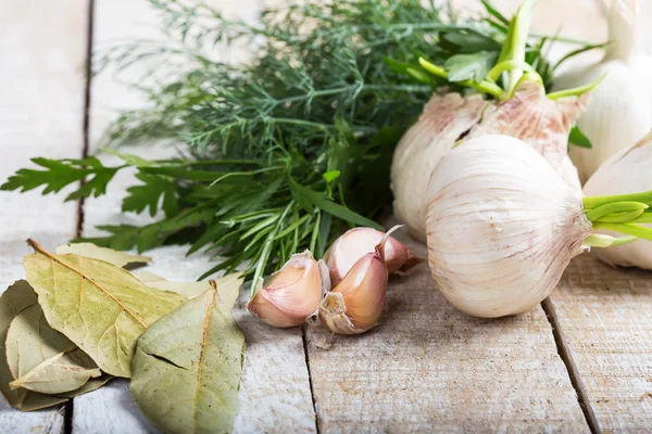 Garlic, herbs, bay leaves on wooden background — Stock Photo, Image
