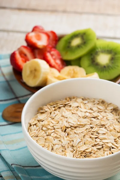 Oat flakes in bowl with fruit — Stock Photo, Image