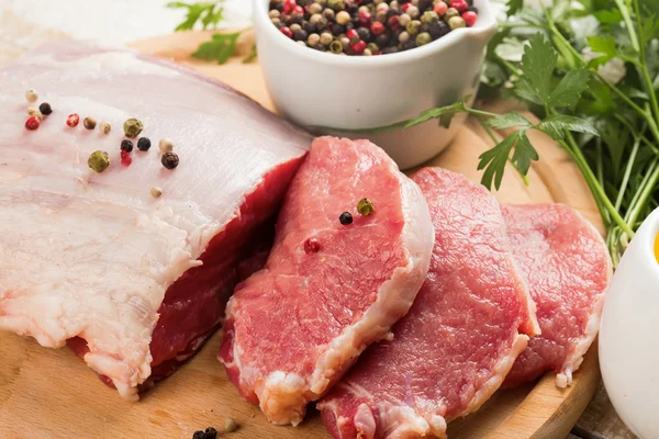 Carne fresca cruda sobre fondo de madera con pimienta — Foto de Stock