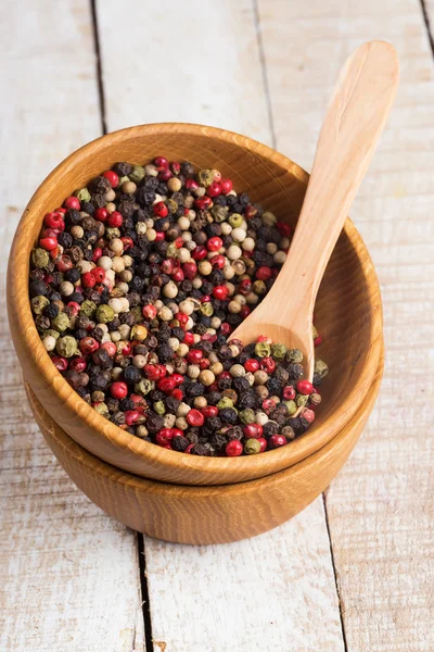 Mixed pepper in wooden can on wooden background — Stock Photo, Image