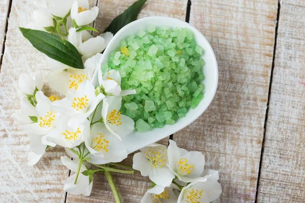 Sea salt in bowl with jasmine on wooden background — Stock Photo, Image