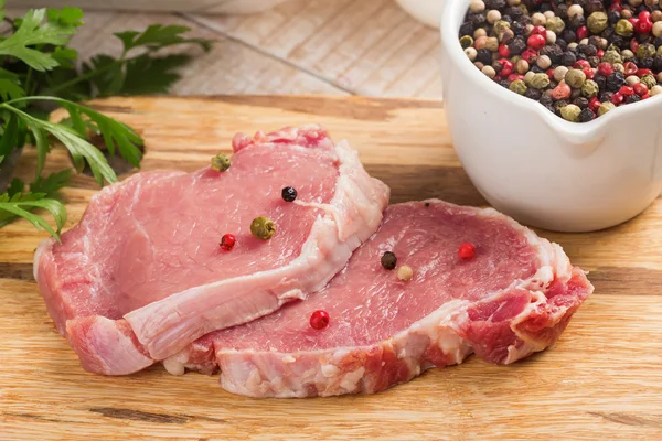 Carne fresca cruda sobre fondo de madera con pimienta — Foto de Stock