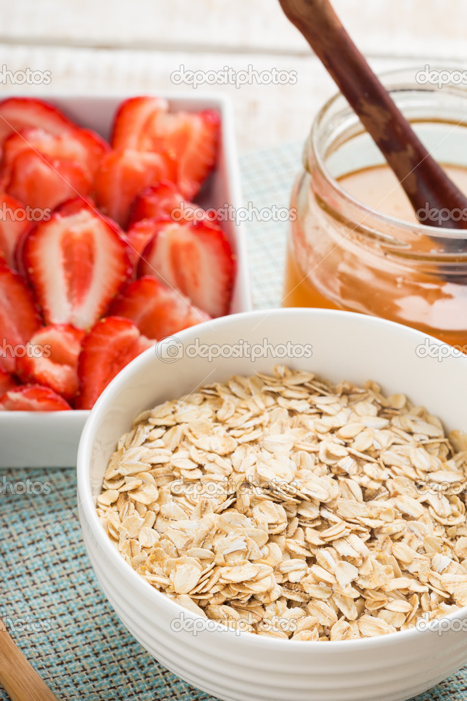 Oat flakes in bowl with strawberry and honey