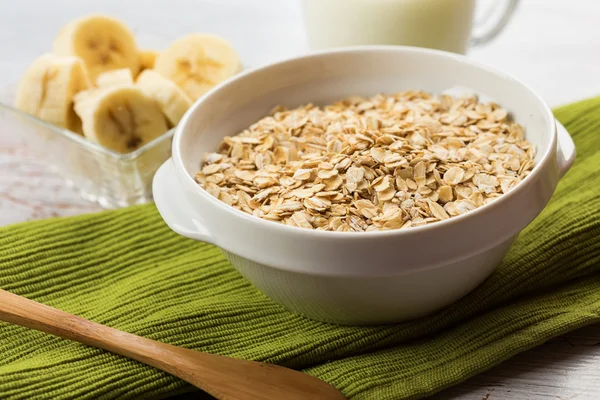 Oat flakes in bowl with banana and milk — Stock Photo, Image