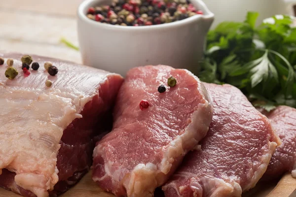 Frisches rohes Fleisch auf hölzernem Hintergrund mit Pfeffer Stockbild