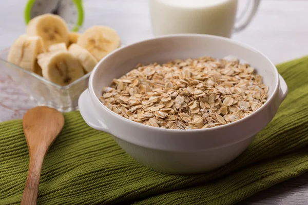 Oat flakes in bowl with banana and milk — Stock Photo, Image