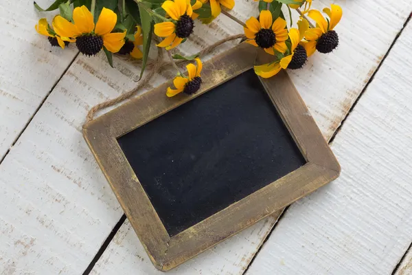 Bando de flores amarelas brilhantes e lousa vazia — Fotografia de Stock