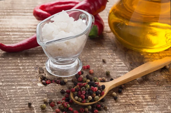 Mixed pepper, sea salt, chili peppers, oil on table — Stock Photo, Image