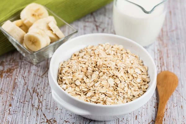 Oat flakes in bowl with banana and milk — Stock Photo, Image