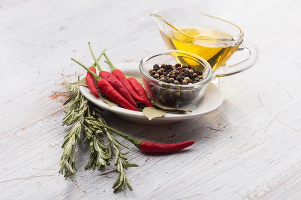 Chili pepper, black peppers, rosemary, oil, bay leaves — Stock Photo, Image