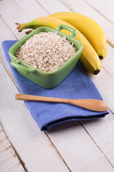 Oat flakes in bowl with bananas — Stock Photo, Image