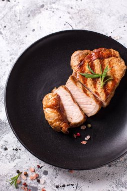 Baharatlı ızgara domuz eti ve siyah tabakta biberiye. Gri desenli arka plan. Üst görünüm.