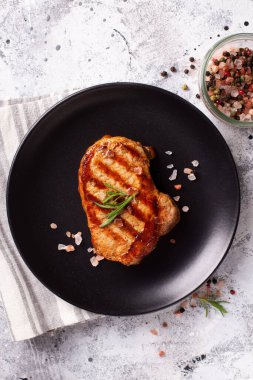 Baharatlı ızgara biftek ve arka planda siyah tabakta biberiye. Üst görünüm.