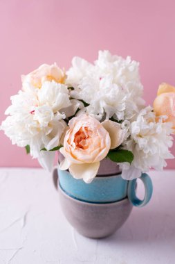 Bir demet renkli yaz gülleri ve şakayık çiçekleri vazodaki pembe arka plana karşı. Seçici odaklanma. Durgun hayat. Kartpostal Yaz konsepti.