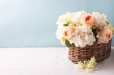 Bir sepet dolusu romantik yaz gülleri, şakayık çiçekleri beyaz desenli arka planda mavi duvara yaslanmış yaşlı böğürtlenler. Seçici odaklanma. Durgun hayat. Metin için yer.