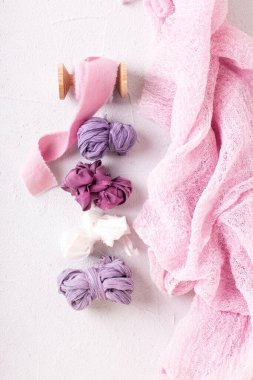 Pembe, lavanta, menekşe, mor ipek kurdele ve dokulu beyaz arka planda havadar peçete. Durgun hayat. Düz yatıyordu. Düğün için. Romantik kartpostal.