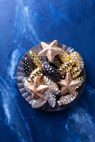 背景与圣诞装饰 玻璃黄金 银质装饰锥和金光闪闪的星星在深蓝色背景的金属板上 简约的风格 安静的生活 顶部视图 — 图库照片