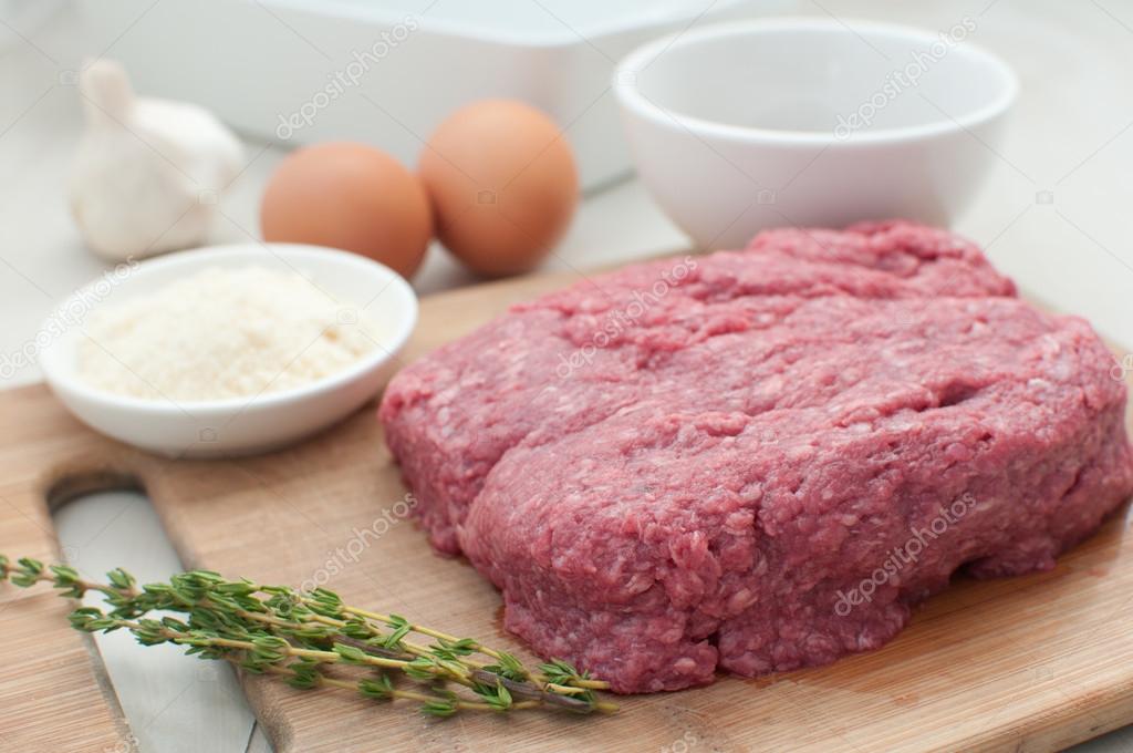 Raw ground meat with eggs and components for cooking