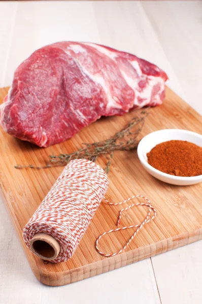 Chunk of raw meat, spices, herbs and twine — Stock Photo, Image