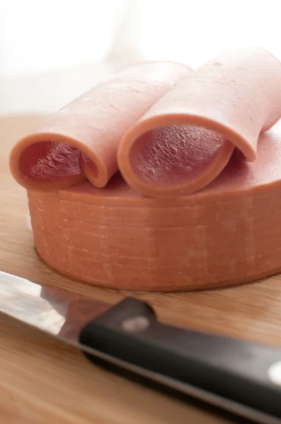Cutting bologna sausage with knife — Stock Photo, Image