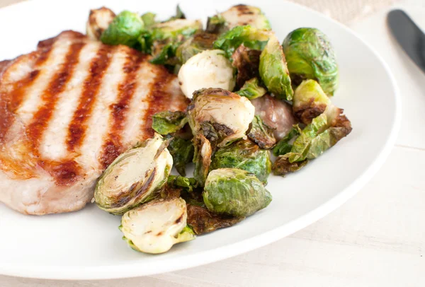 Cut brussels sprouts and pork chop — Stock Photo, Image