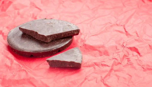 Dark chocolate on red holiday background — Stock Photo, Image