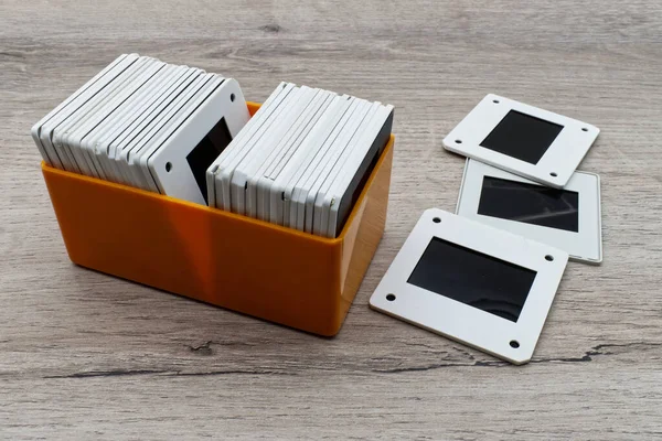 Plastik bir kutuda eski slaytlar. Tahta masanın üzerinde 35 mm 'lik eski bir slayt filmi..