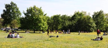 Bolonya - İtalya - 18 Nisan 2022: İnsanlar park çimlerinde dinleniyor. Salgından sonra parkta dinleniyorlar. Bolonya, İtalya.