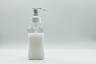 Şeffaf plastik şişe ve şeker kutusu. Beyaz zemin üzerinde beyaz sıvı krem izole edilmiş tam konteynır.