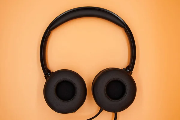 Modern Black Headphones Isolated Orange Background Top View — ストック写真