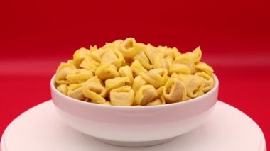 Raw Tortellini rotating on a red background. Traditional Italian pasta