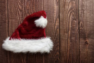 Kırmızı Noel Baba şapkası ahşap arka planda izole edilmiş. Mesaj için yer var. Düz yatıyordu.