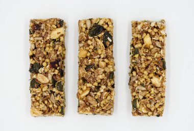 Beyaz arka planda kepekli fıstık ve kızılcıklı protein çubuğu..