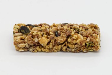 Beyaz arka planda kepekli fıstık ve kızılcıklı protein çubuğu..