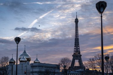 Günbatımında renkli gökyüzü olan Paris 'teki Eyfel kulesini ve Ortodoks katedralini seyret.