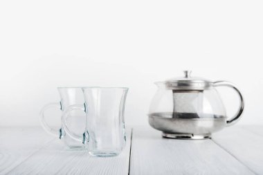 İki boş şeffaf bardak ve ahşap ışıklı arka planda boş şeffaf çaydanlık yakın plan ve boşluk kopyala..