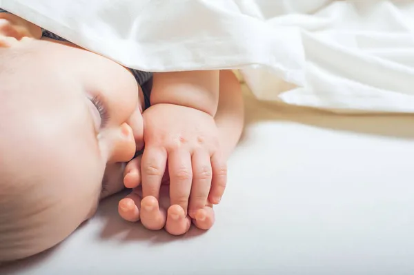 Bebek rüyasında yatakta parmağını emiyor. Bebek istirahat uykusu, yanlış ısırık, diş çıkarma, kolik.... — Stok fotoğraf
