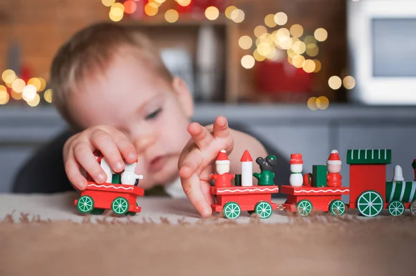 Toddler boy playing with Christmas train in kitchen close-up... — стоковое фото