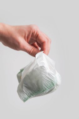 Hand holds dirty used diaper for garbage..