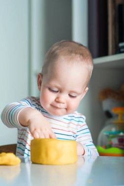 Küçük çocuk masada sarı plastikinle oynuyor. Çocuklarda iyi motor becerilerin gelişimi..