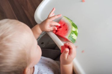 Yukardaki sandalyede sulu olgun karpuz yiyen çocuk manzarası..