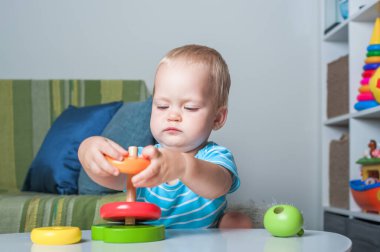 Çocuk odasında eğitici tahta ve plastik oyuncaklarla oynayan yakışıklı çocuk..