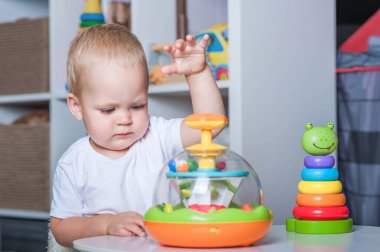 Çocuk odasında eğitici tahta ve plastik oyuncaklarla oynayan yakışıklı çocuk..