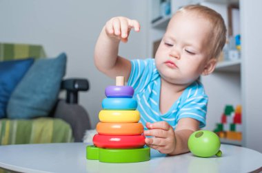 Çocuk odasında eğitici tahta ve plastik oyuncaklarla oynayan yakışıklı çocuk..