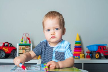 Toddler boy draws with felt-tip pen, developing games for preschoolers.